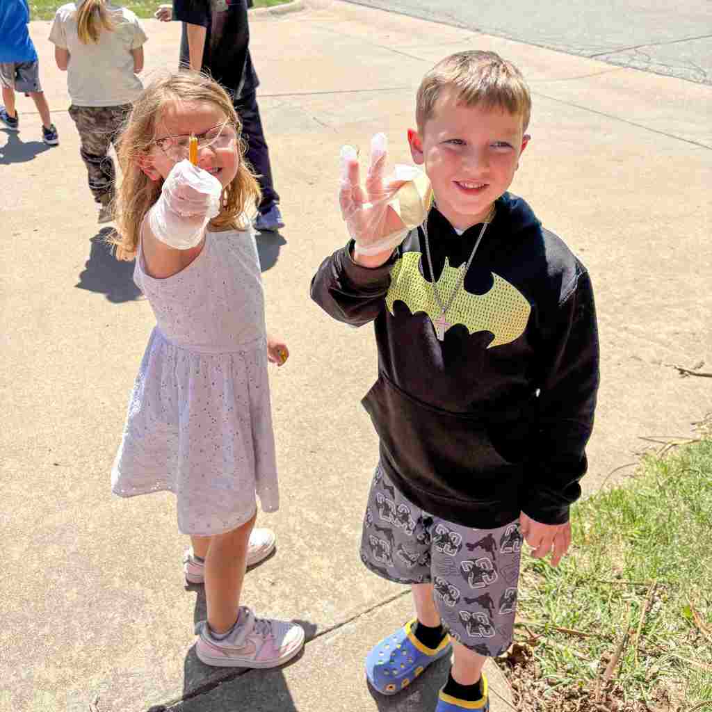 two students proudly holding up the trash they found
