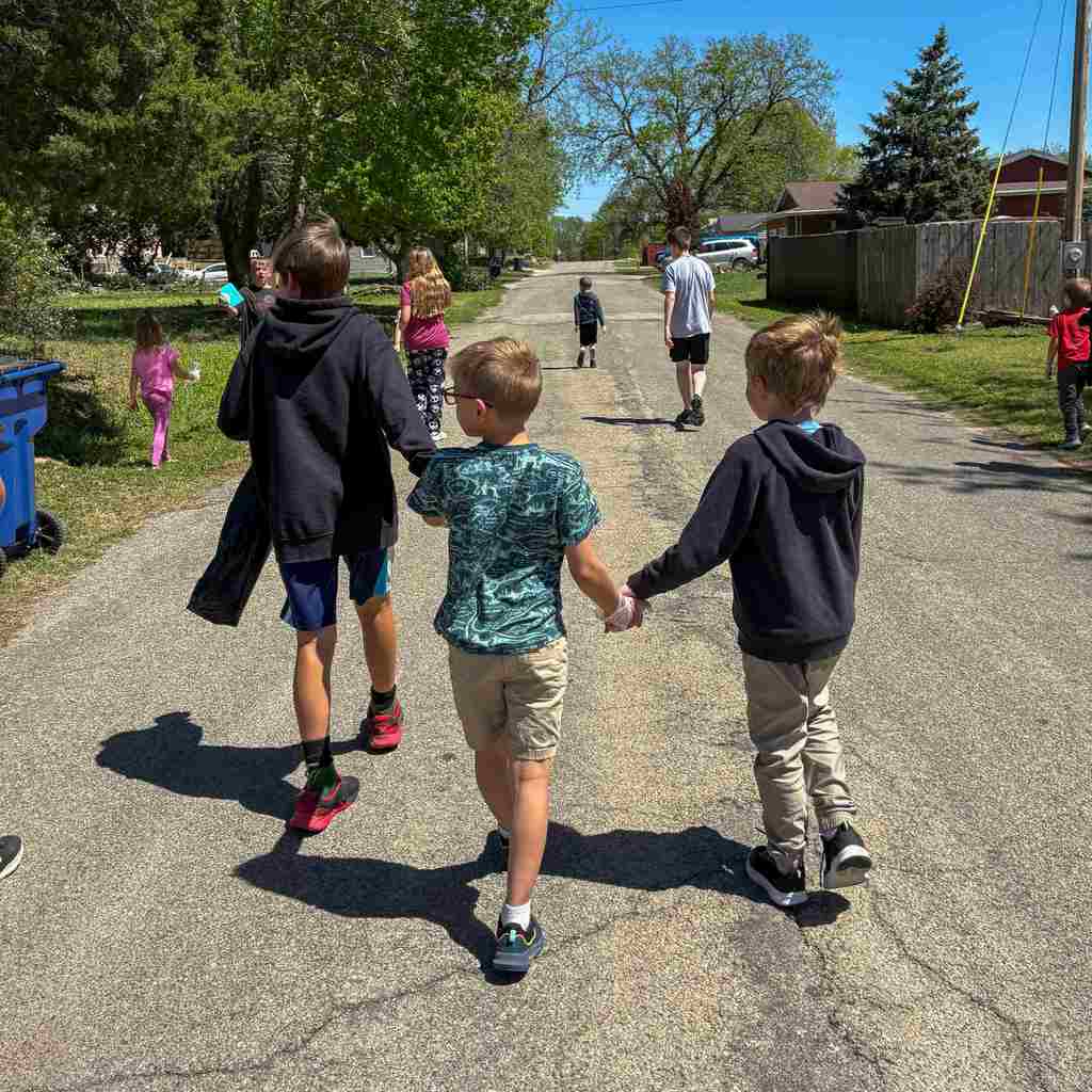 three students holding hands walking down the road