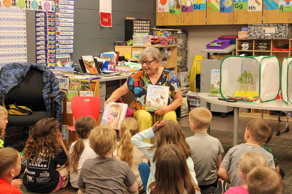 Sherry showing a photo of her granddaughter with a butterfly on her hair to a group of students.