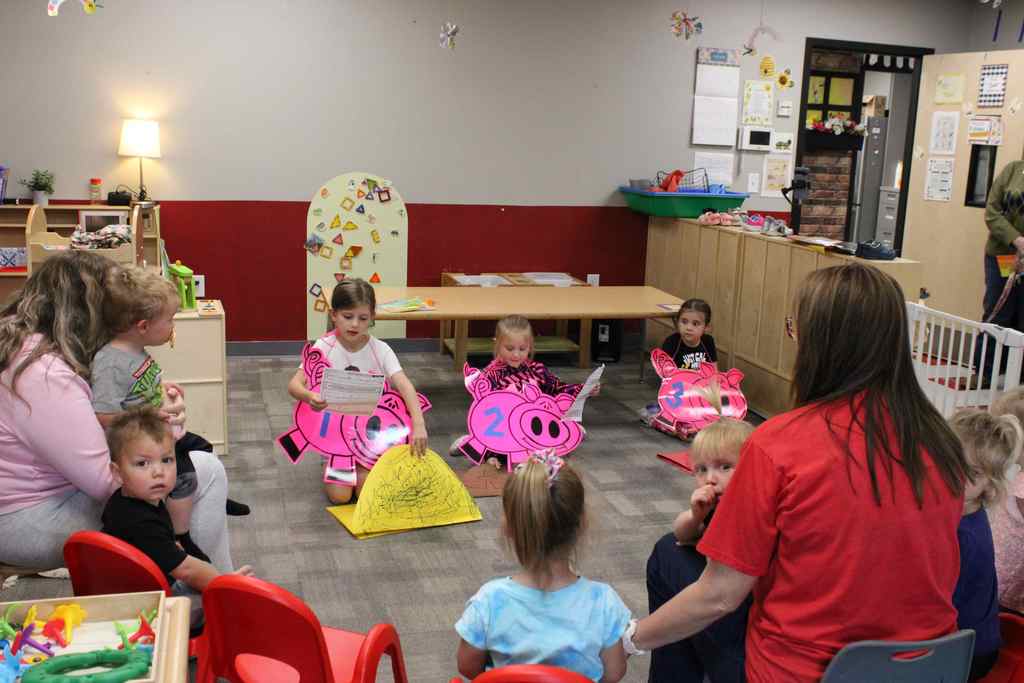 long range shot of the actors and the crowd watching. three students dressed up as the three little pigs