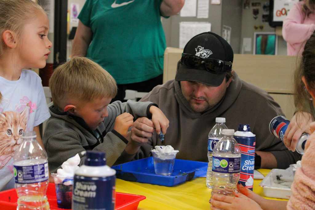 A close-up of students working with colorful materials during a classroom art or science lesson.