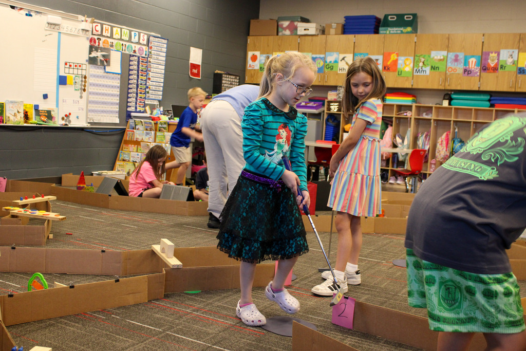 two young students, one with a golf club, one looking on