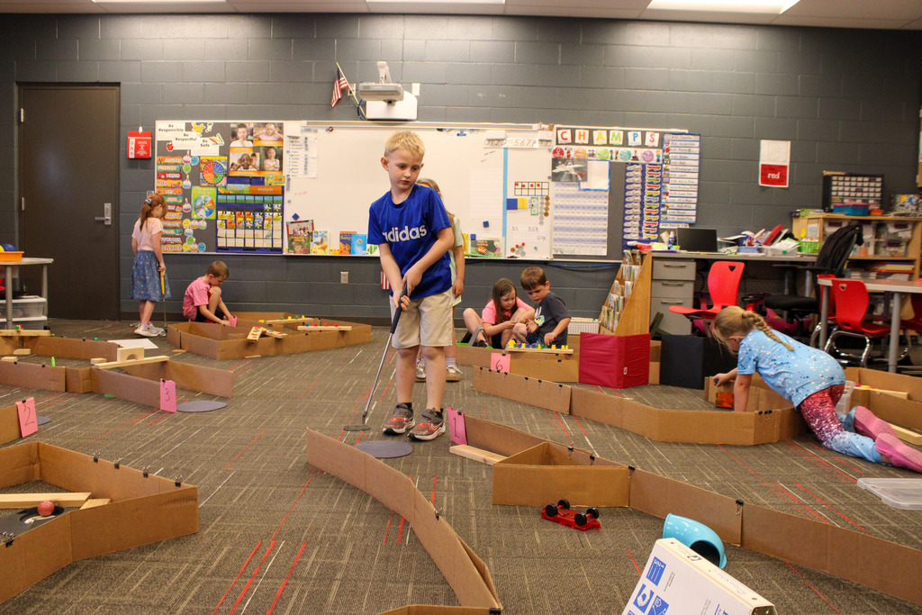 one young student actively playing their mini-golf set