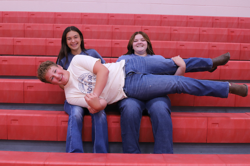 Brielle and Abbigail holding Jordan in their laps laughing