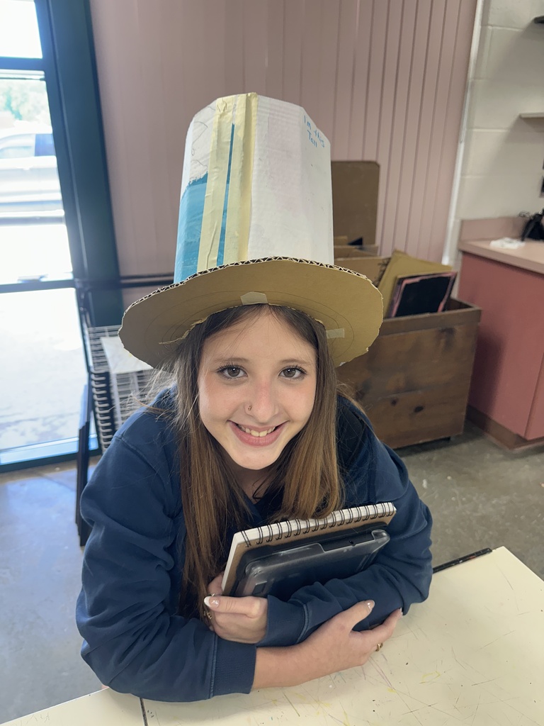 student smiling while wearing their handmade cardboard tophat