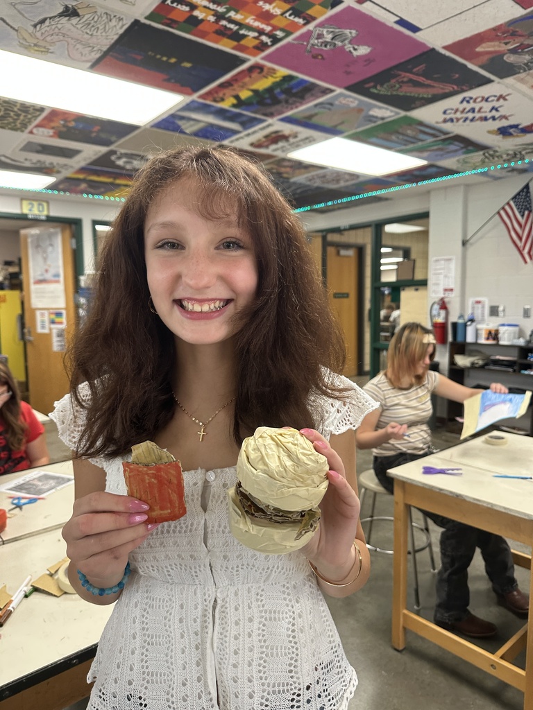 student holding their handmade burger and fries that are made out of cardboard