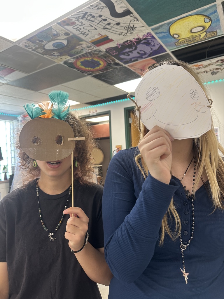 two students holding up handmade masks to their face