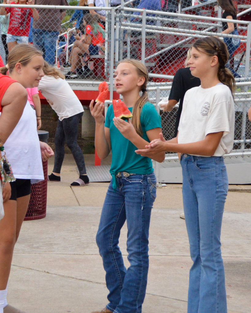 middle school students standing around eating watermelon