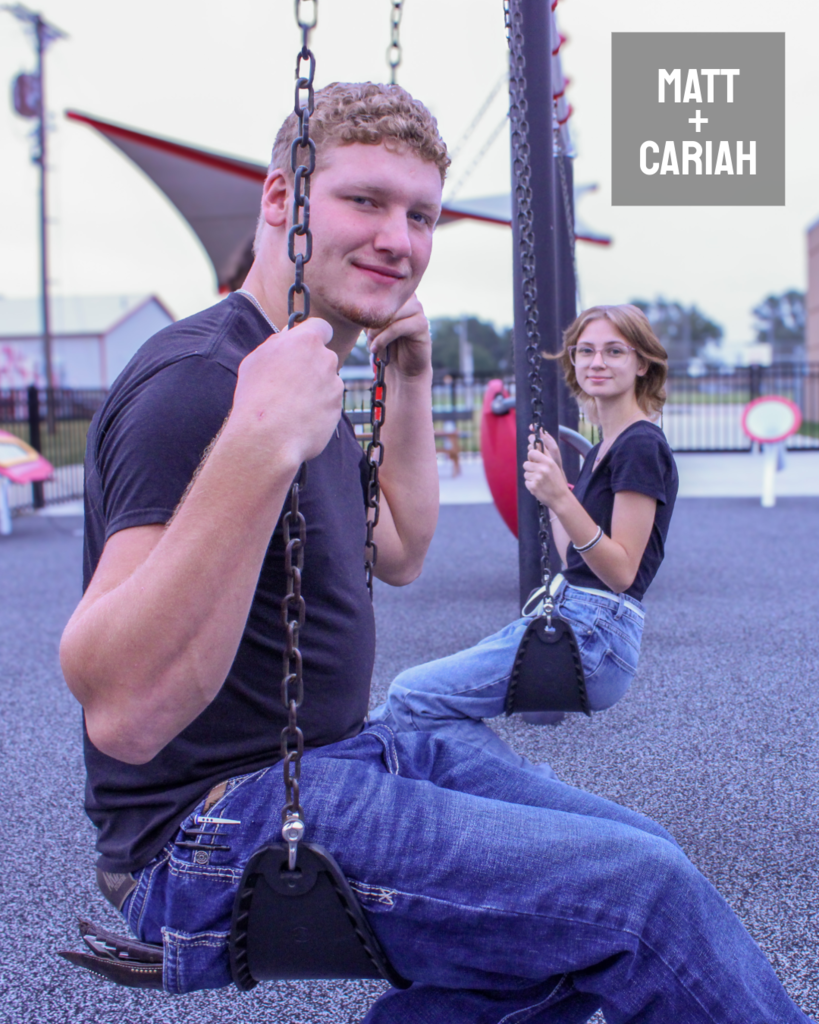 two homecoming students sitting in a swing facing opposite directions and looking at the camera