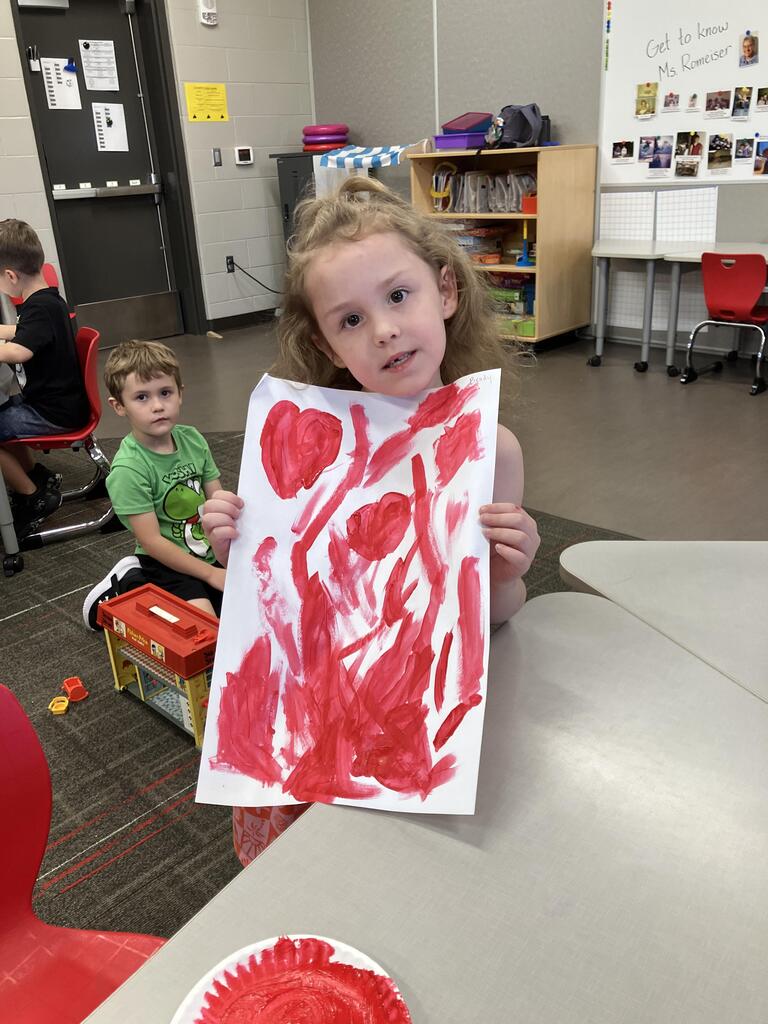students painting with red paint on white paper