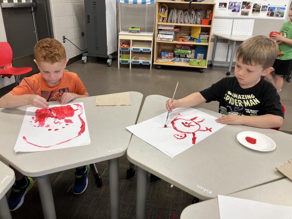 students painting with red paint on white paper