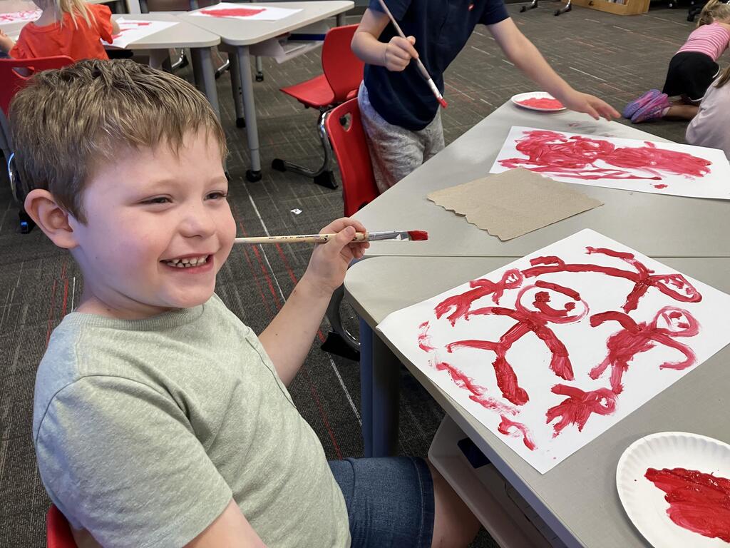 students painting with red paint on white paper