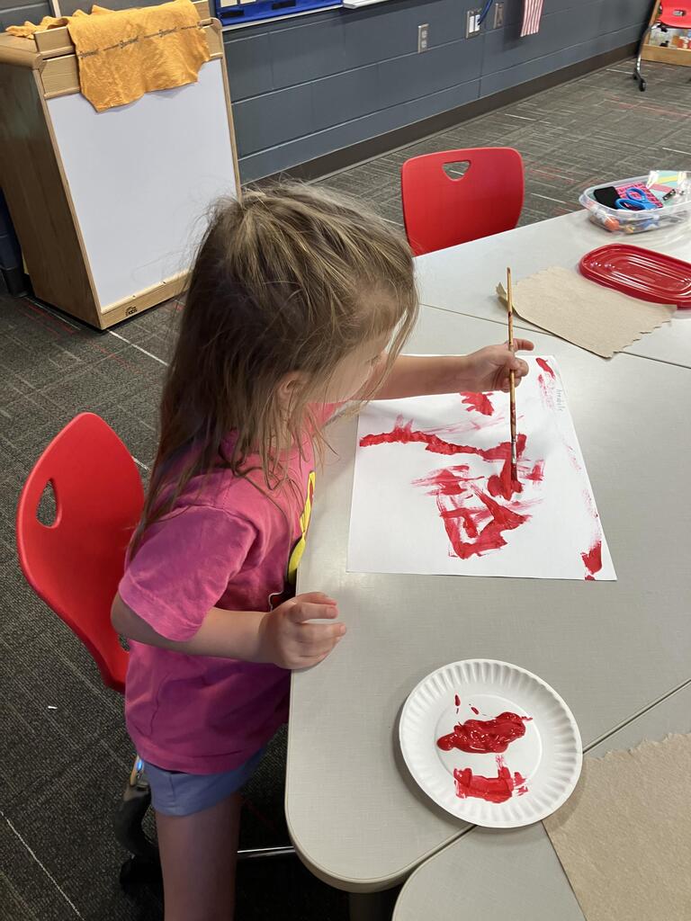 students painting with red paint on white paper