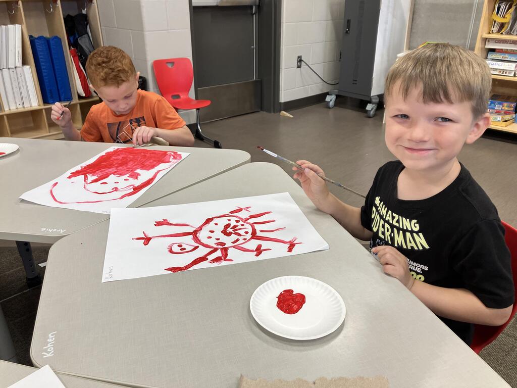 students painting with red paint on white paper