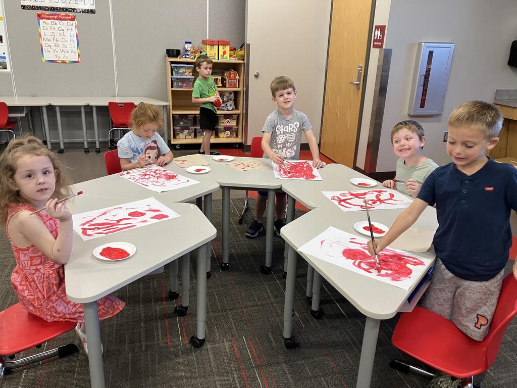 students painting with red paint on white paper