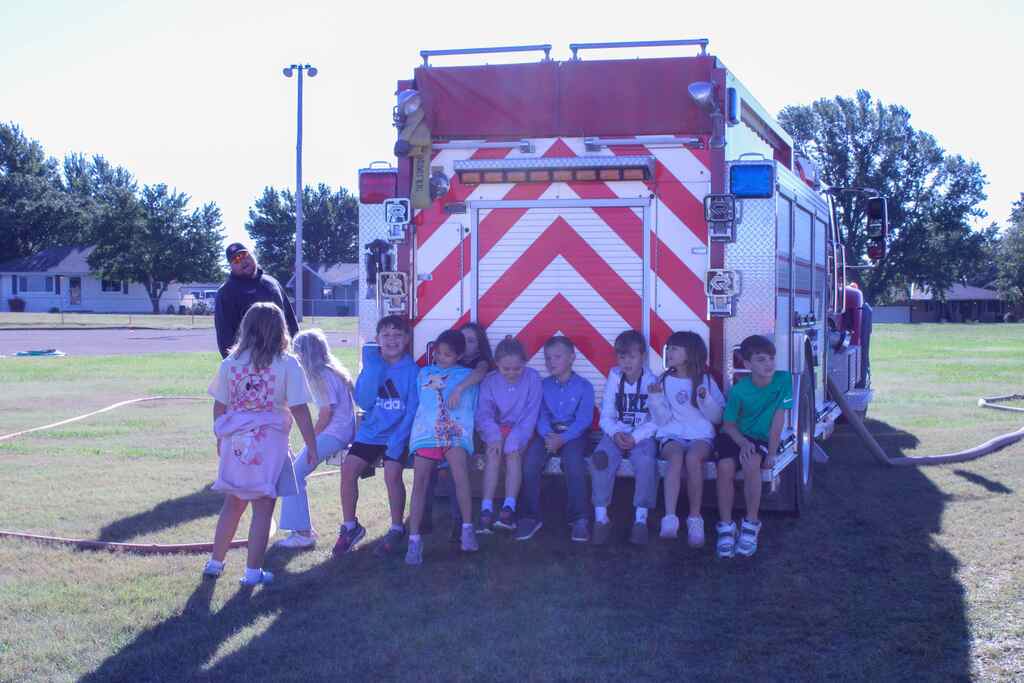 group of students sitting on the back of the fire truck