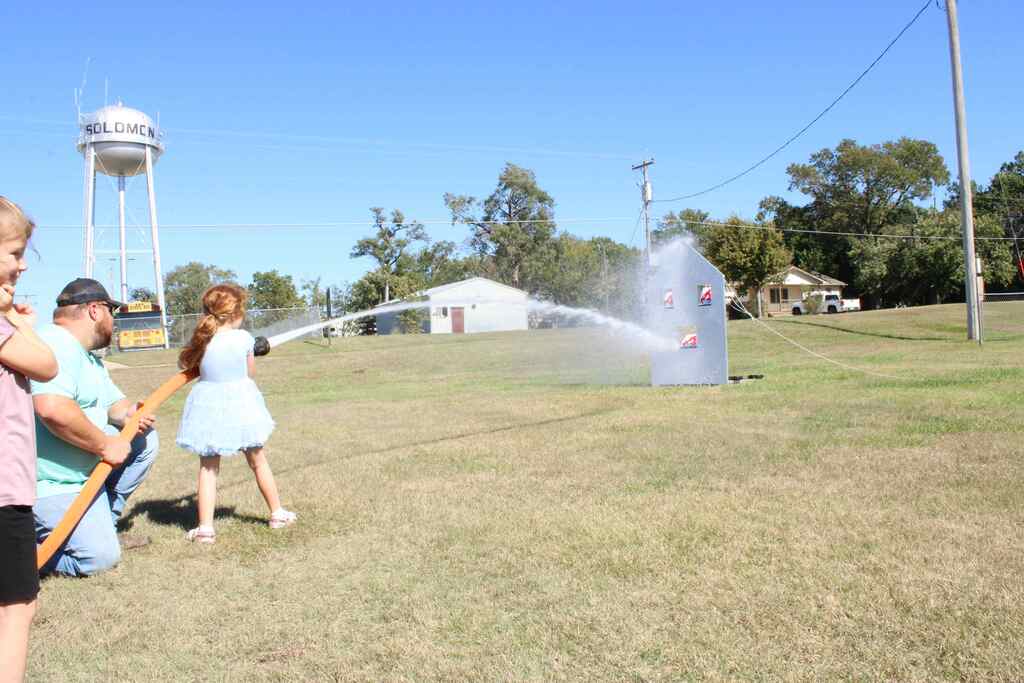firefighter helping student with a water hose