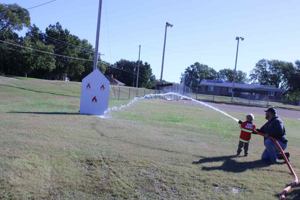 firefighter helping student with a water hose