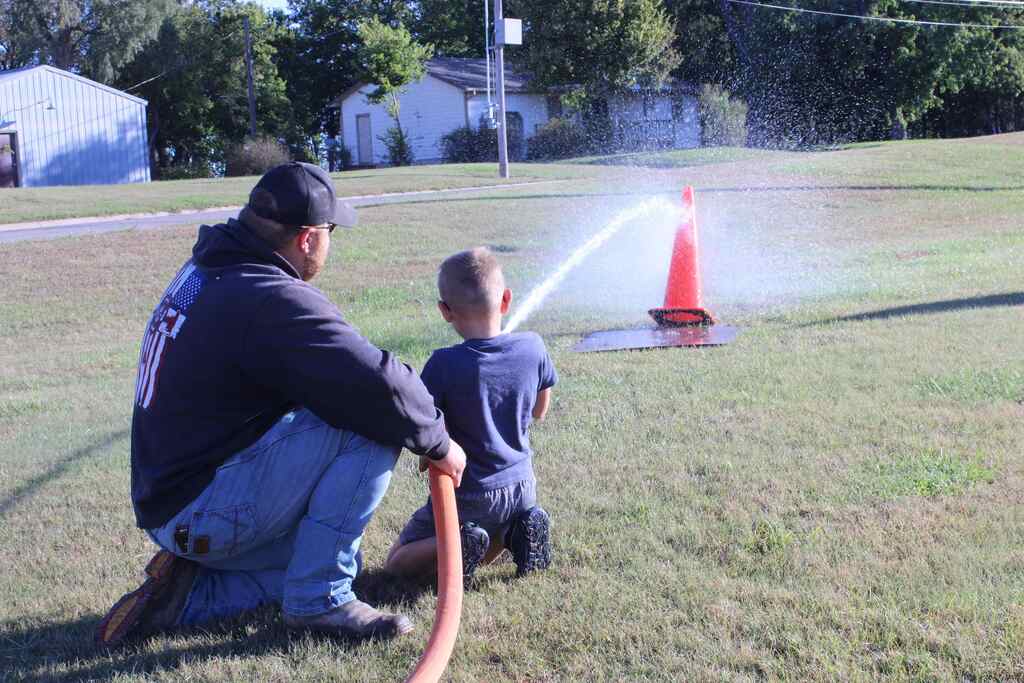 firefighter helping student with a water hose