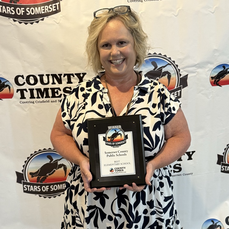 Woman in front of a backdrop, holding a plaque and smiling