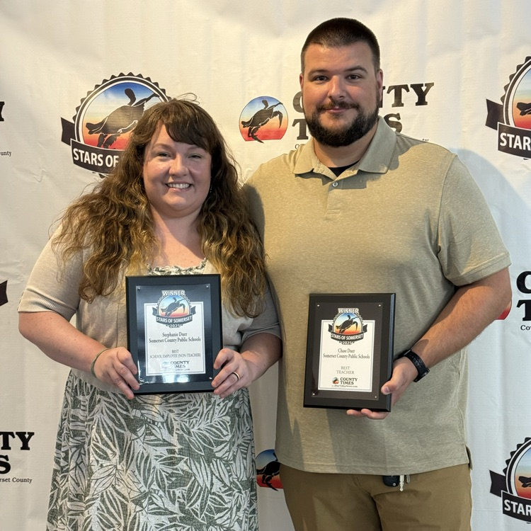 men and women standing in front of a backdrop holding plaques