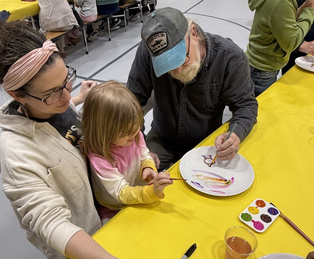 pictures of families enjoying a dinner plate painting craft at DIS' American Education Week Event