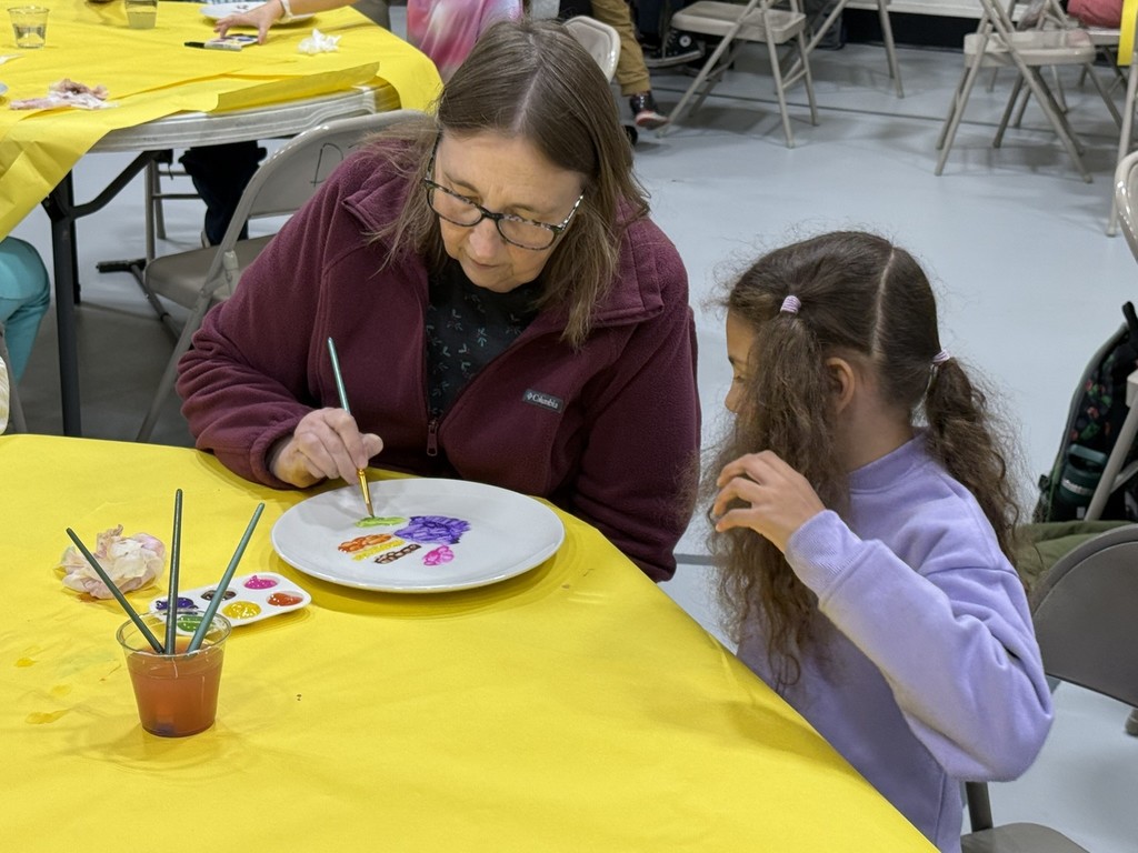 pictures of families enjoying a dinner plate painting craft at DIS' American Education Week Event