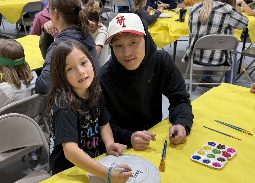 pictures of families enjoying a dinner plate painting craft at DIS' American Education Week Event
