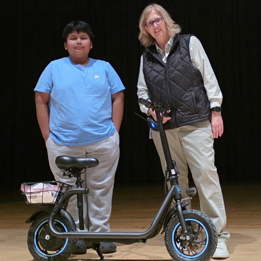 Bryan with his new electric scooter presented by Ms Davis. 