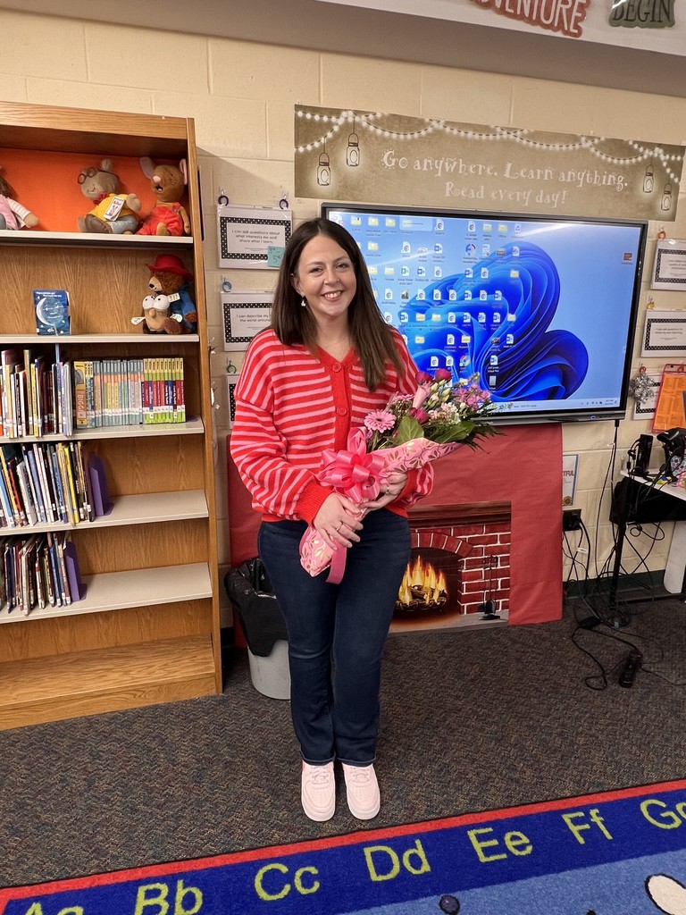 Picture of teacher holding flowers in a classroom