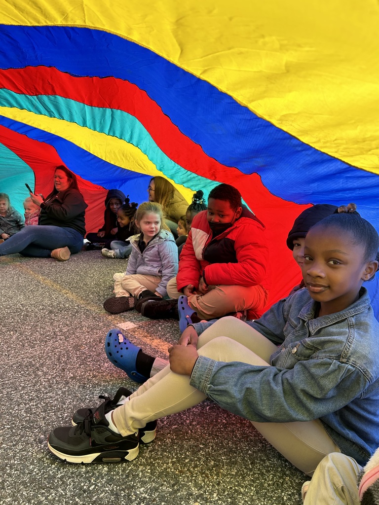 students sitting under a color parachute