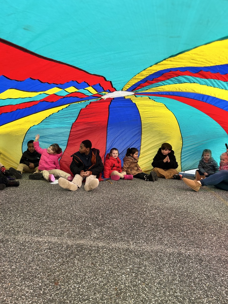 students sitting under a colorful parachute
