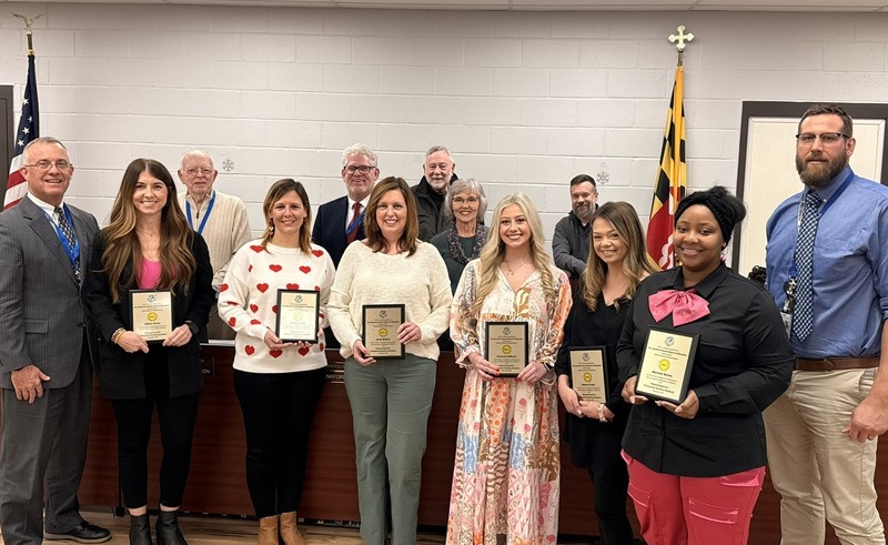 teachers and board members holding plaques and smiling