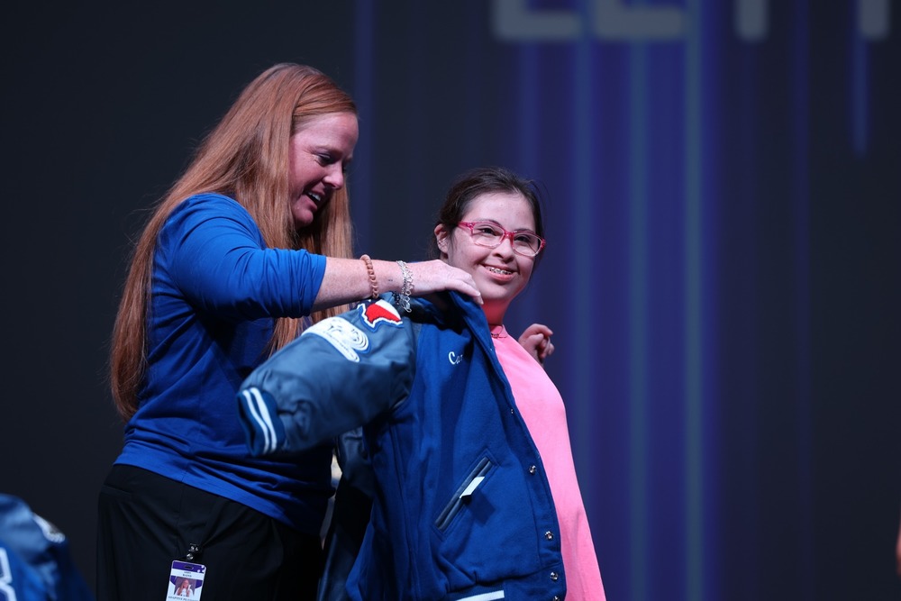 Coach rains placing a jacket on student