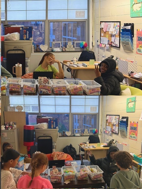 A two-photo vertical collage shows students helping operate a classroom prize cart while other students browse reward items.  Top photo: Two students sit behind a row of clear plastic bins arranged across a table. Each bin has a pink price label reading “$20 Vanderbucks.” The bins contain small toys, stickers, fidget items, and assorted prizes. One student sits behind a laptop decorated with stickers, while the other sits beside the display. Behind them is a classroom wall with a bulletin board, organized paper holders, educational posters, and classroom supplies. Large windows provide natural light and reveal brick buildings outside. One visible poster reads, “It’s OKAY to feel your FEELINGS.”  Bottom photo: Several younger students stand at the table examining prize choices. The same row of labeled prize bins stretches across the foreground. A student seated behind the table appears to be helping or monitoring the selection process while using a laptop. The classroom setting includes a desk, storage contain