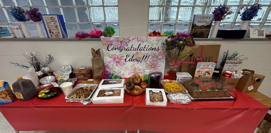 Table with red tablecloth displaying a variety of baked goods and a sign saying "Congratulations Grads!!!"