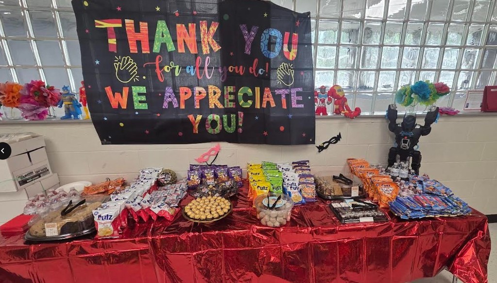 A table covered in red foil with snacks and a banner saying "Thank You! We Appreciate You!" in colorful letters.