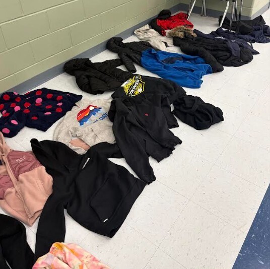 Multiple jackets of various colors and styles are laid out in a line on a white floor.