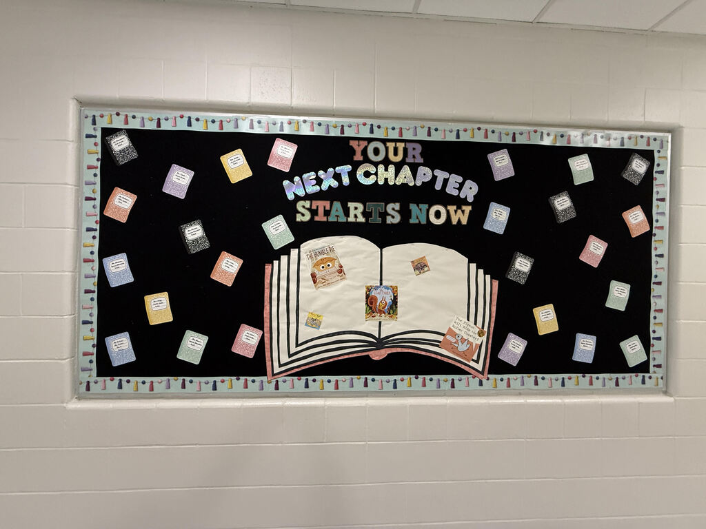 Bulletin board with "Your Next Chapter Starts Now" written on it. An open book displays a story and surrounded by colorful stickers.