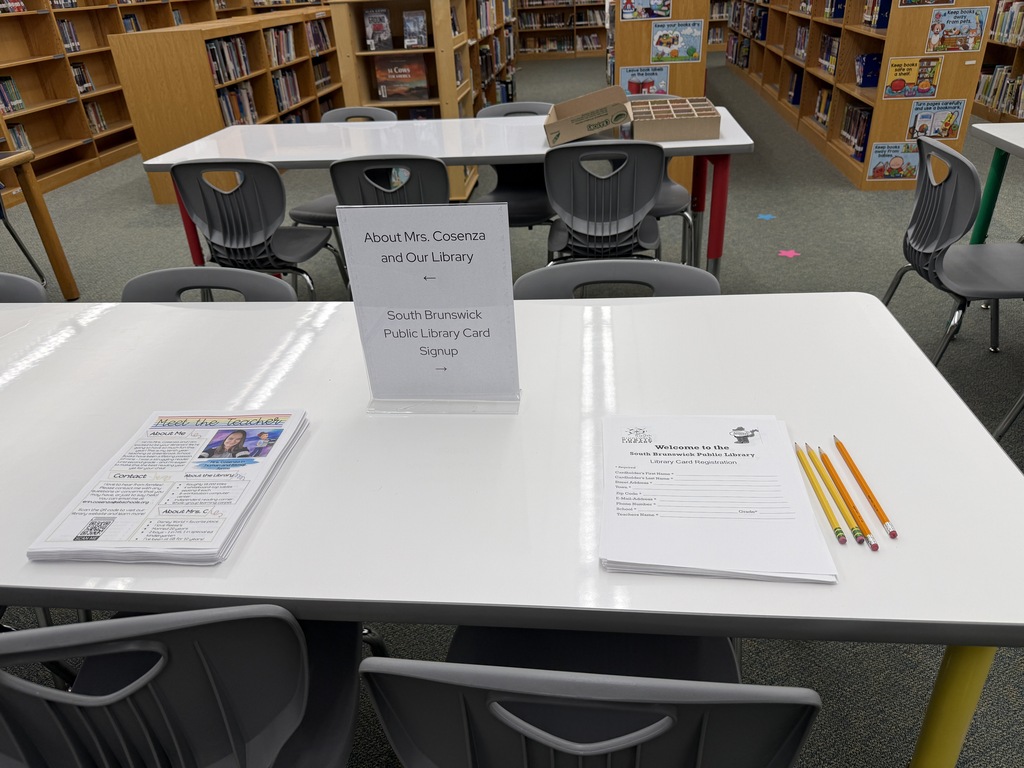 An empty library with tables and chairs. One table has books and colored pencils on it.