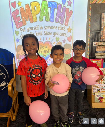 Three children stand in a room, each holding a pink balloon, with a large "Empathy" poster in the background.