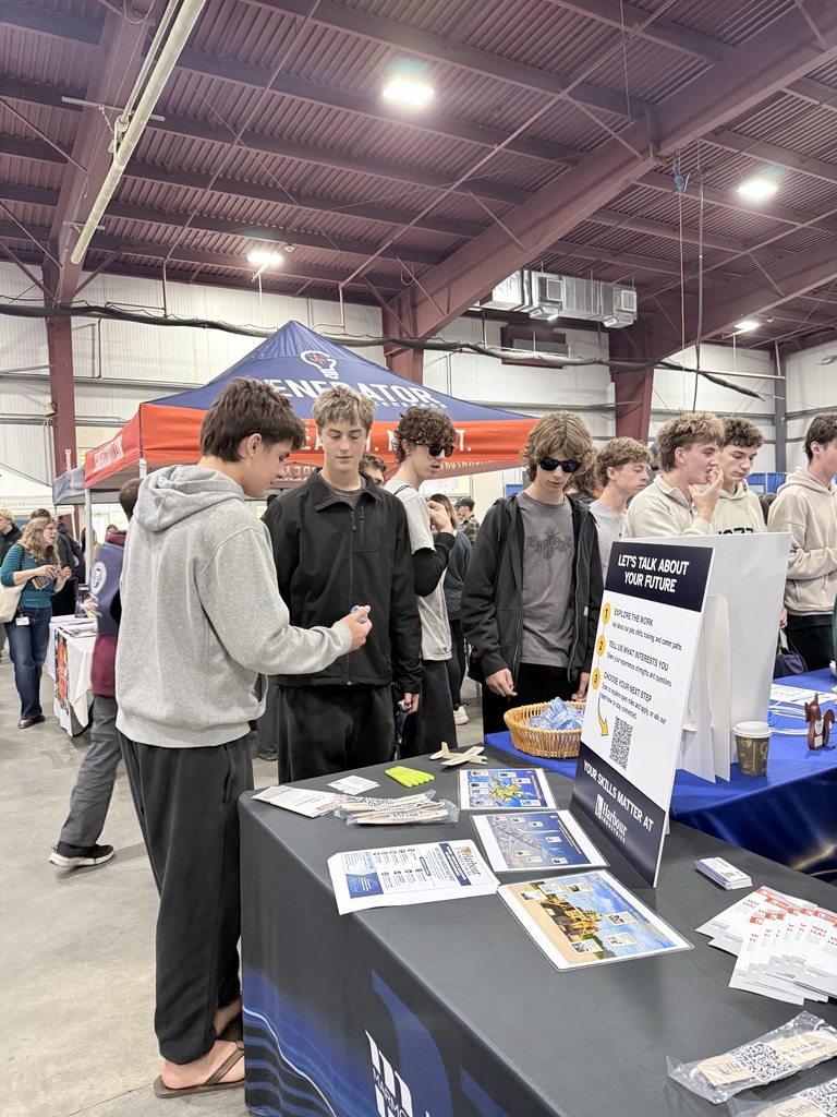 Group of people at a table with brochures and flyers. One person looks at a pamphlet.