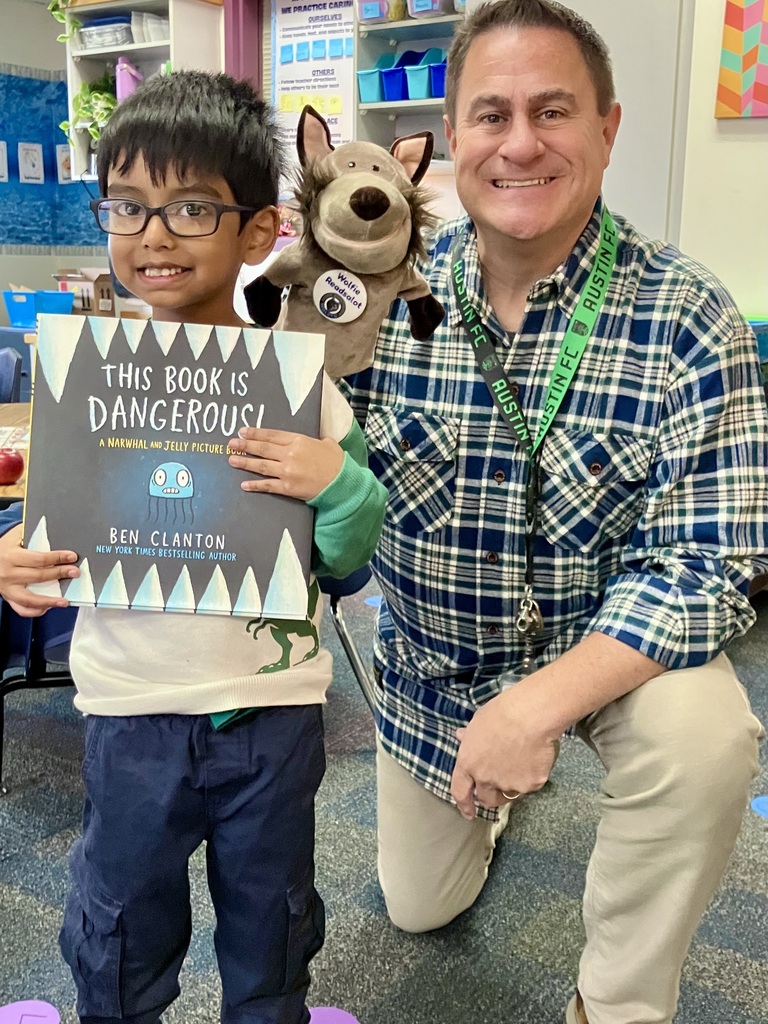 Man in plaid shirt kneeling next to a boy holding a book titled "This Book Is Dangerous".