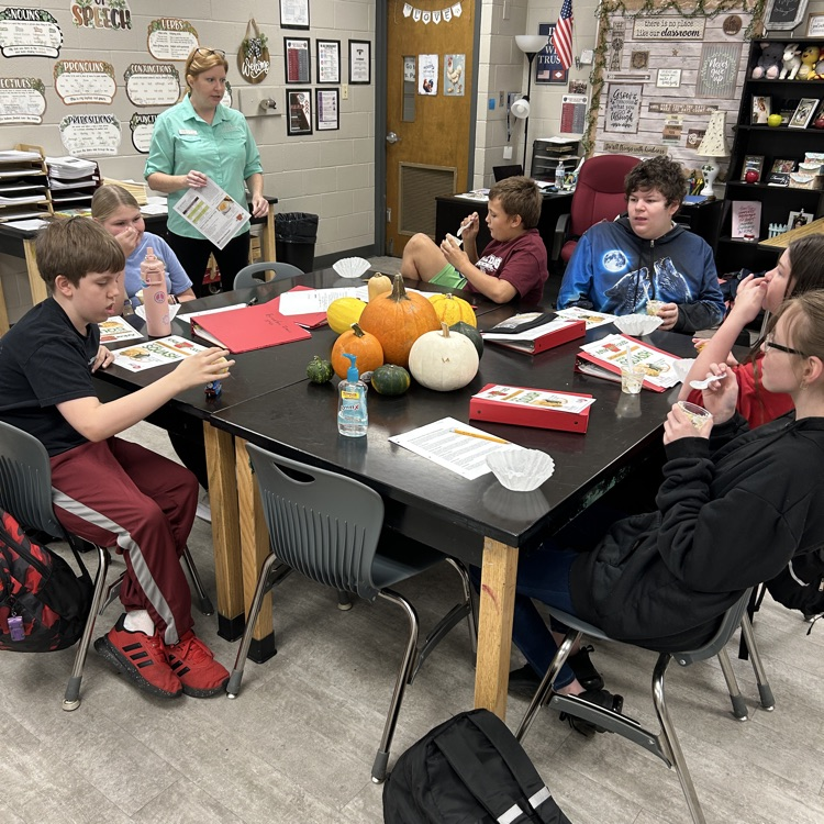 Students gathered around table listening to Ms. Autrey