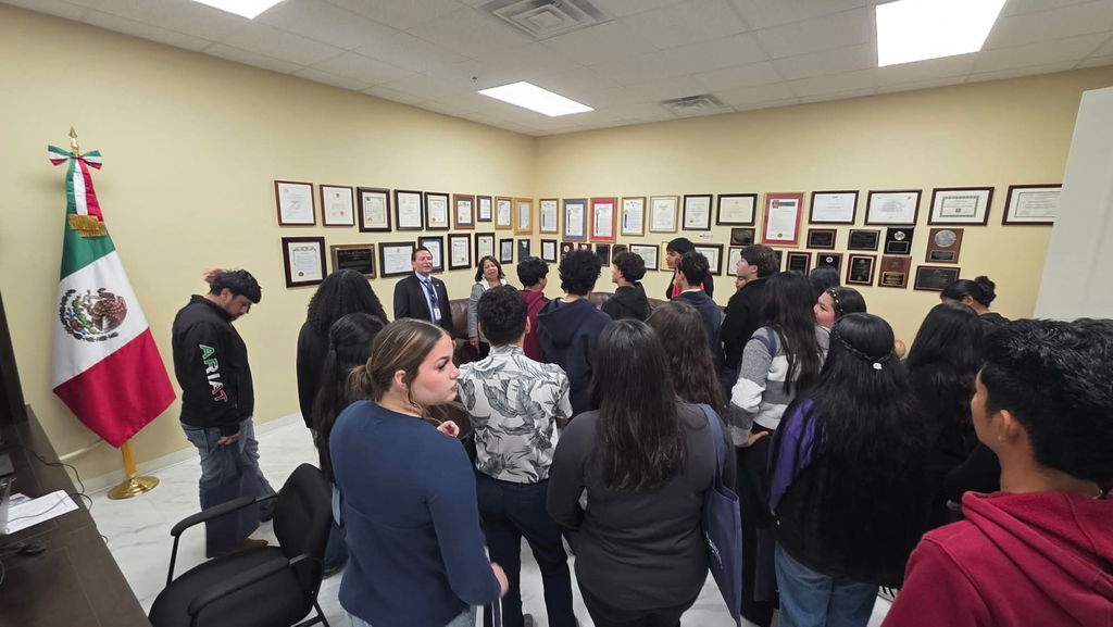 group of students standing in the Mexican Consulate, listening to a speech