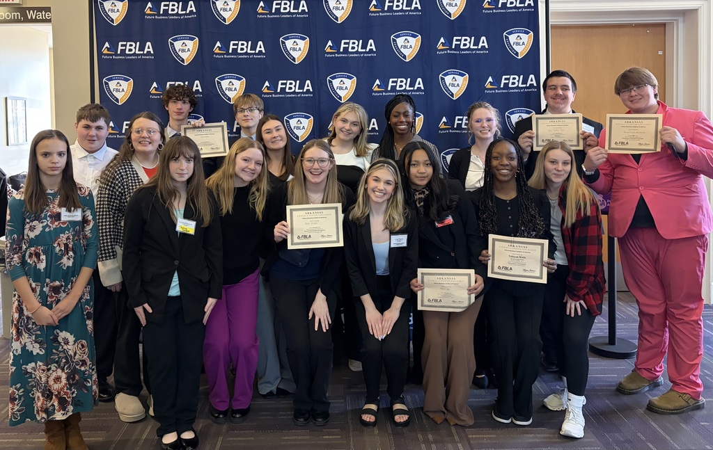 group of students in front of FBLA banner, holding competition certficates