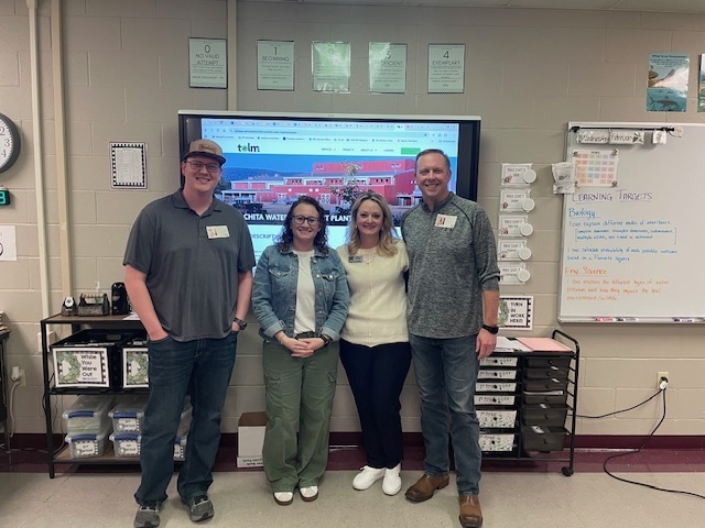 4 adults posing for a picture at the front of a classroom