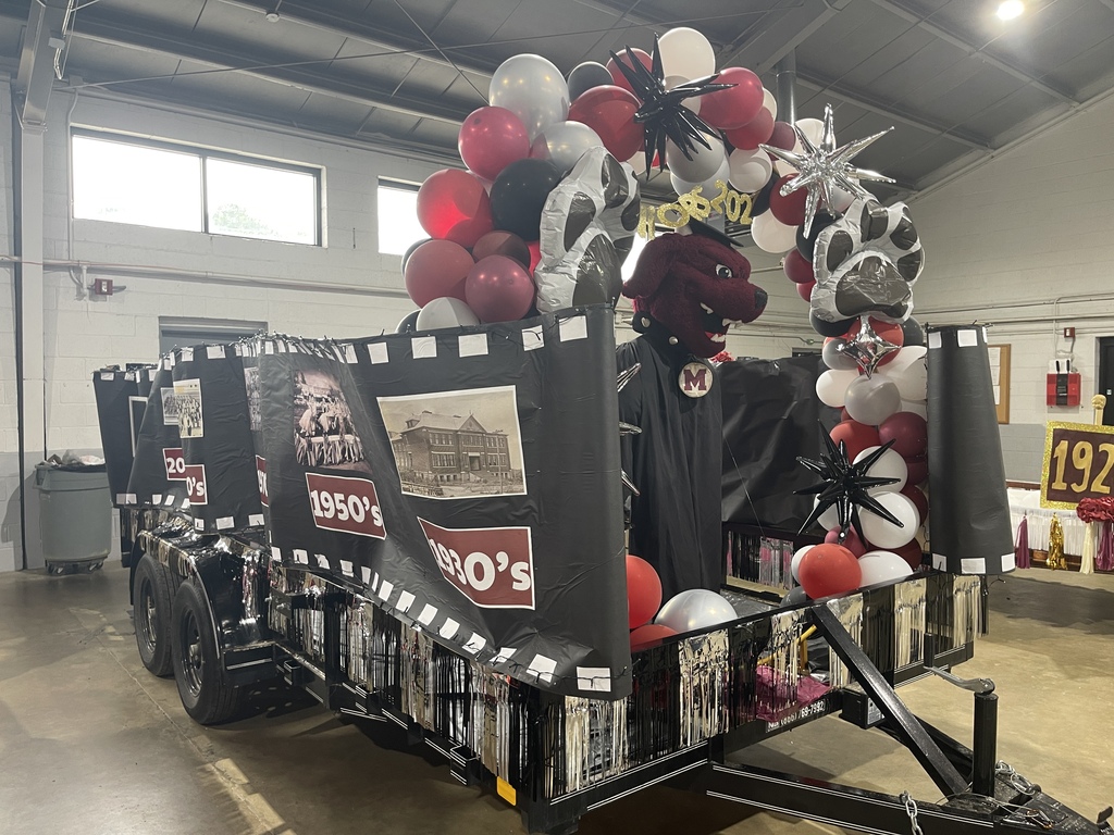 A trailer loaded with a large arch of balloons and posters with black, red, white, and silver colors.