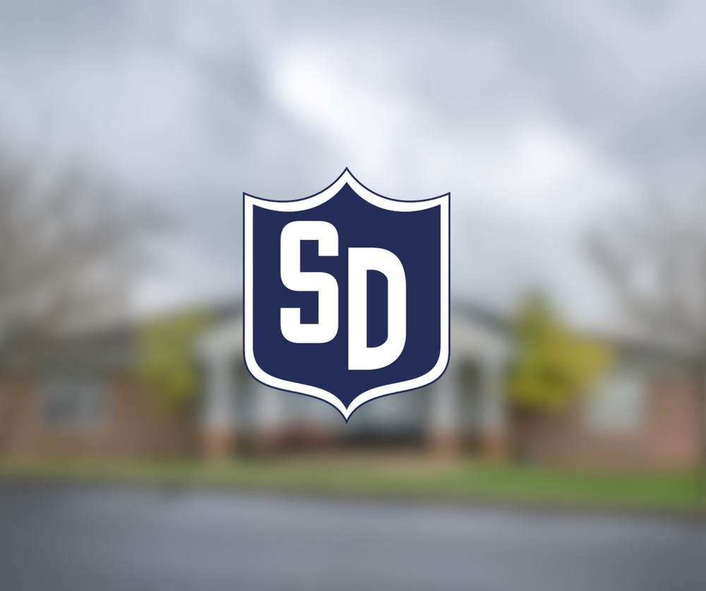 SDCSC Shield Logo over photo of SDCSC Corporation Office