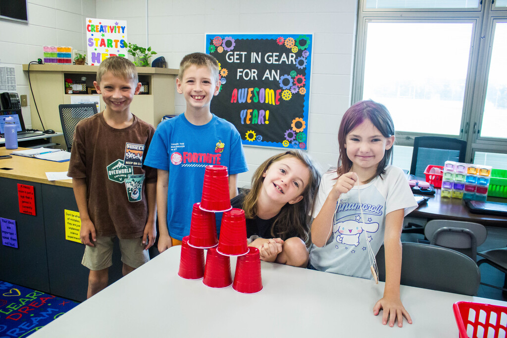 AES  students attempt cup stacking through string.